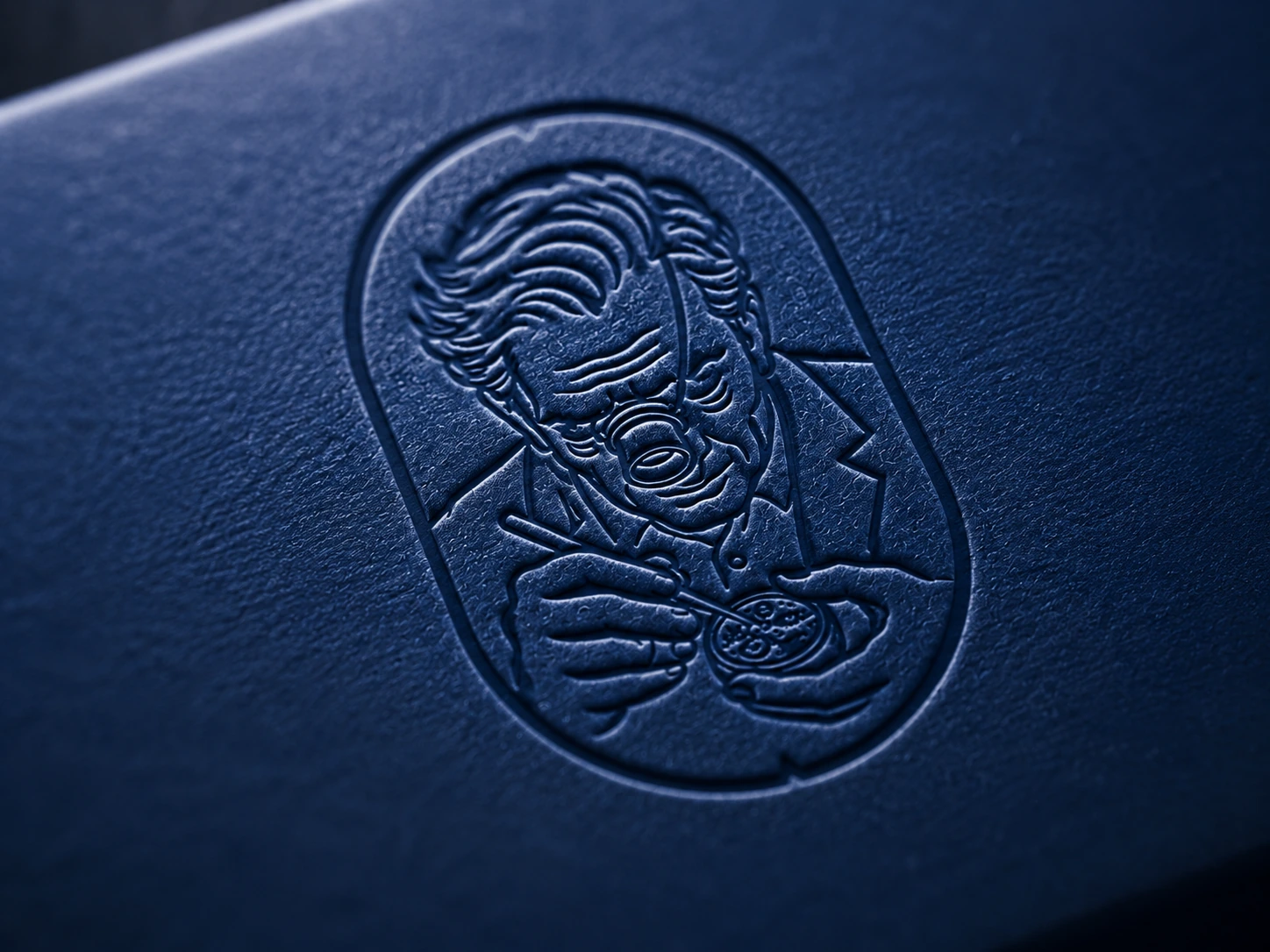 Golden Ring close up of embossed portrait mark in navy leather texture